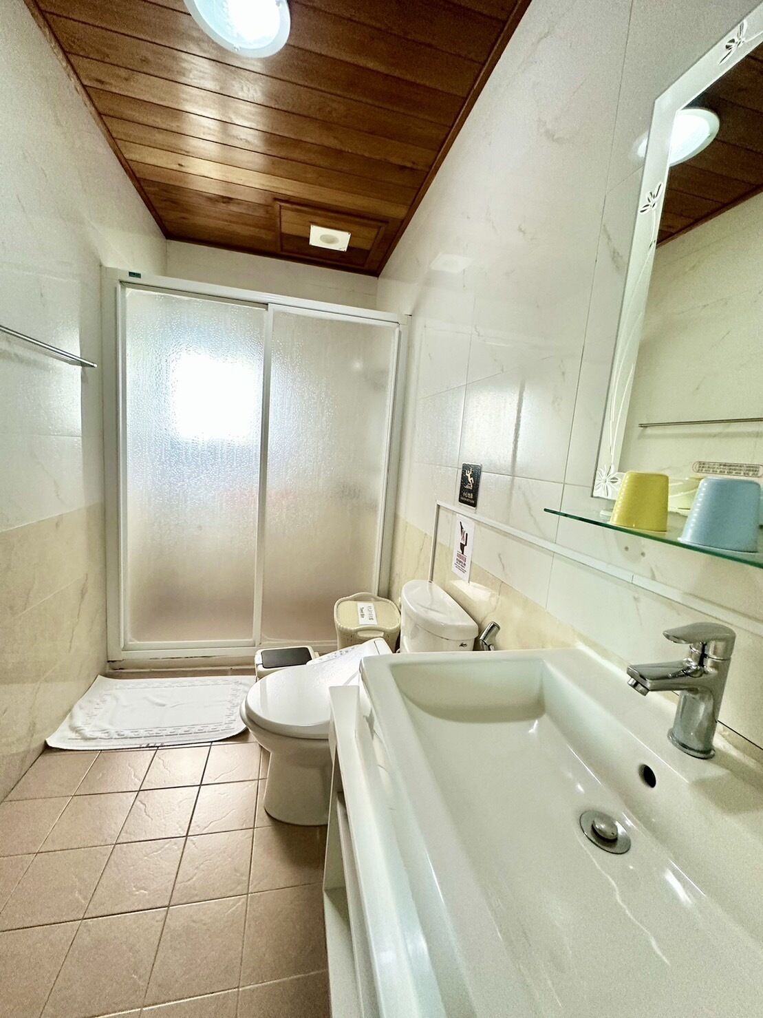 A bathroom with a shower, toilet, sink, and mirror.
