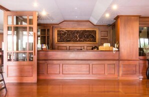 Un espace d’accueil avec un comptoir de réception en bois, une grande œuvre d’art accrochée au mur et une porte en verre.