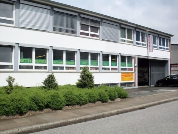 A building with multiple windows, some with green signage, and a garage door.
