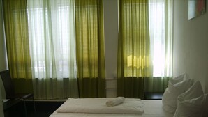 Ett hotellrum med en säng, en stol och gardiner.