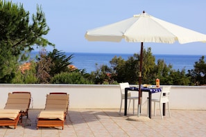 A terrace with two sun loungers, a table with chairs, and a white umbrella. - Sa Fiorida Case Vacanze (Valledoria)