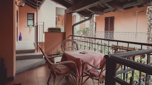 Un balcón con muebles de mimbre y una mesa, con vistas a un jardín.