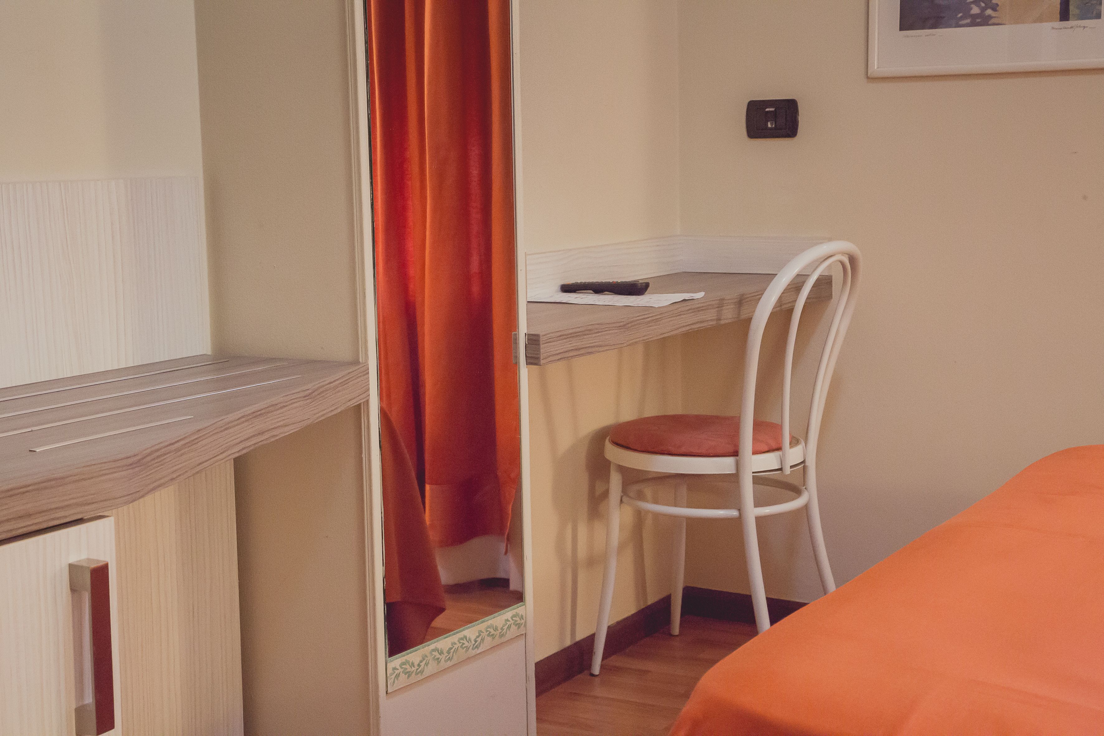 A room with a bed, a desk with a chair, and a curtain.