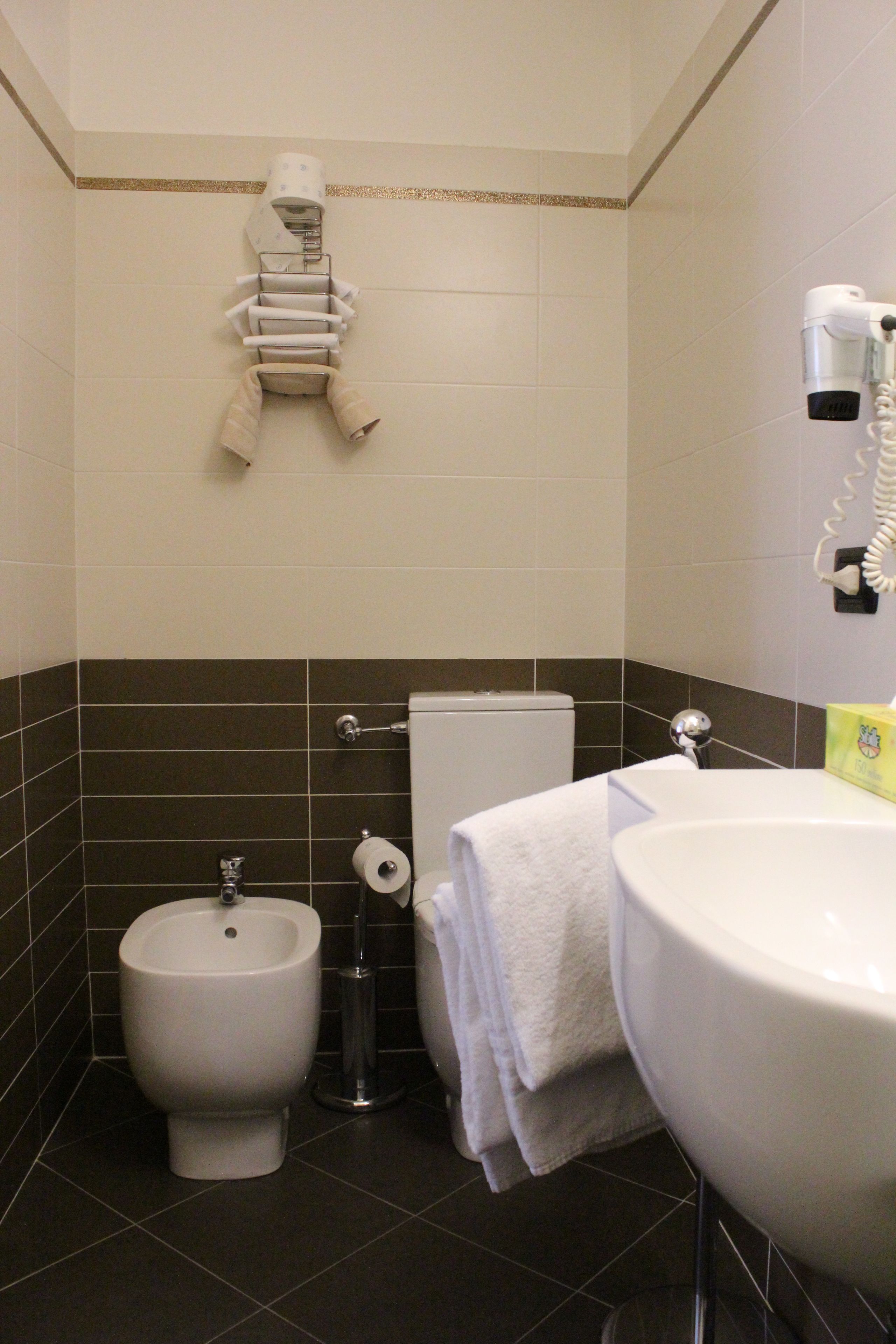 A bathroom with a bidet, toilet, and sink.