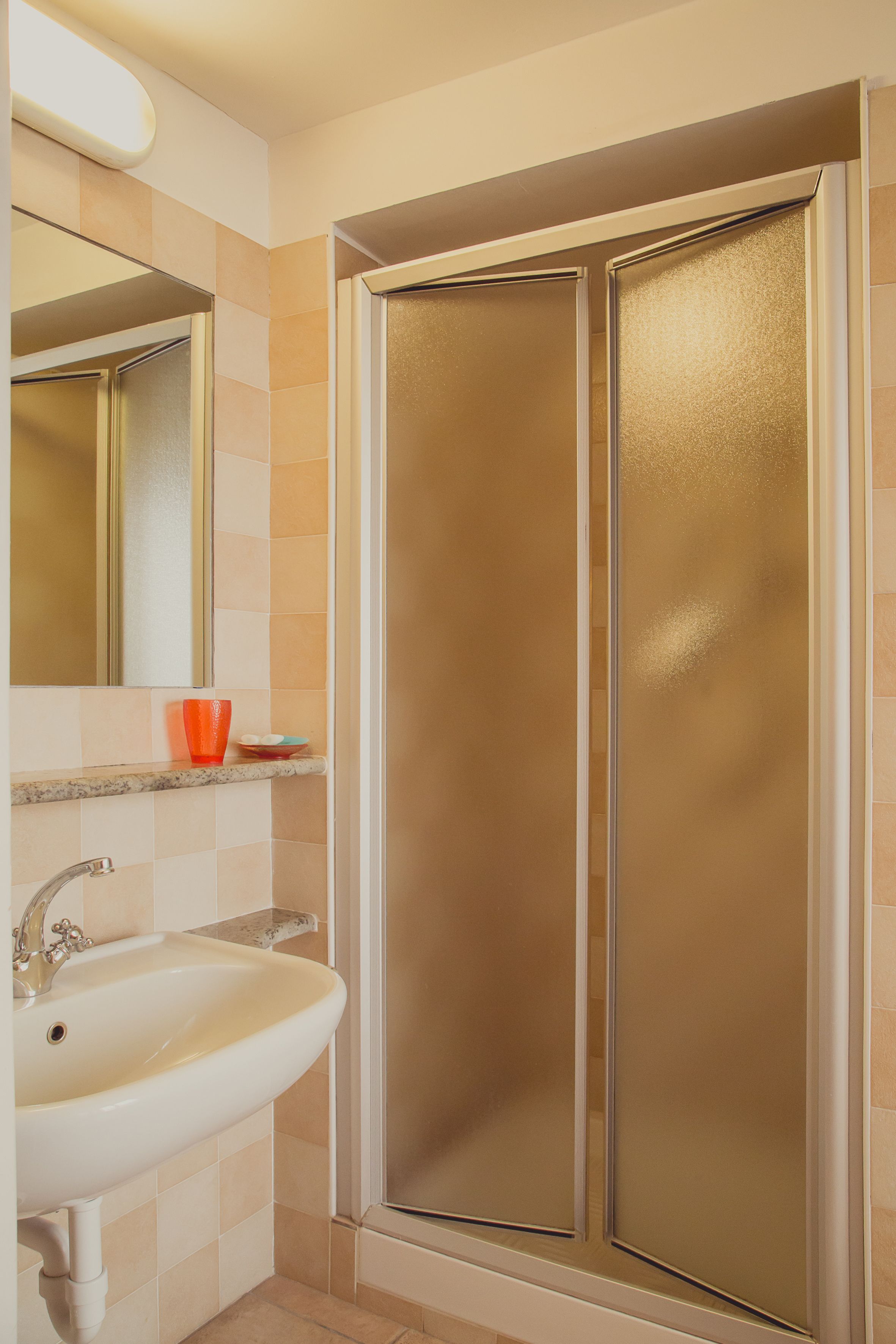A bathroom with a sink, mirror, and shower enclosure.