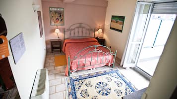 Una camera da letto con una struttura del letto in metallo, una coperta rossa, due lampade da comodino, un tappeto decorato e un'ampia finestra con vista.