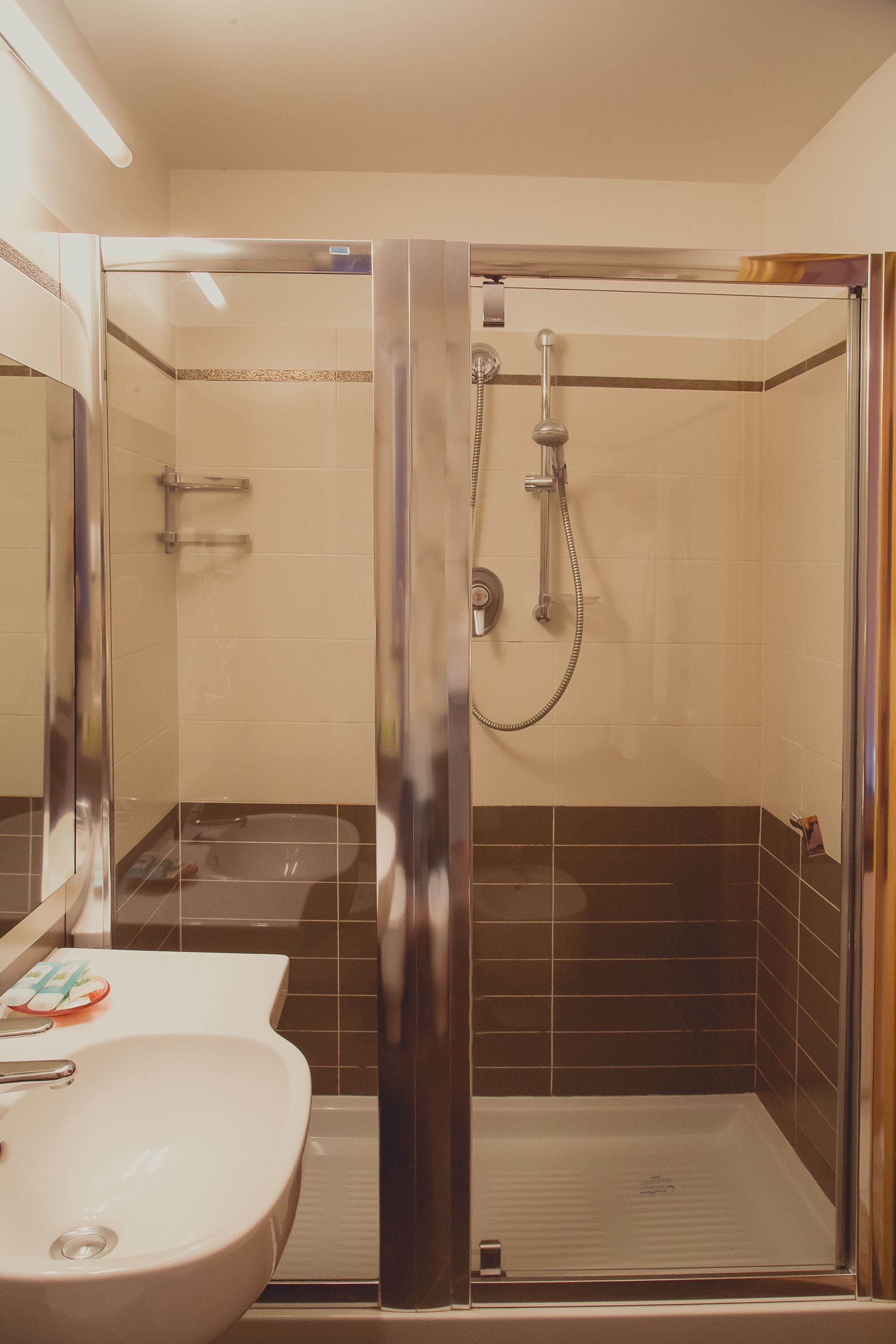 Une salle de bain avec une douche à parois de verre, un lavabo et un miroir.