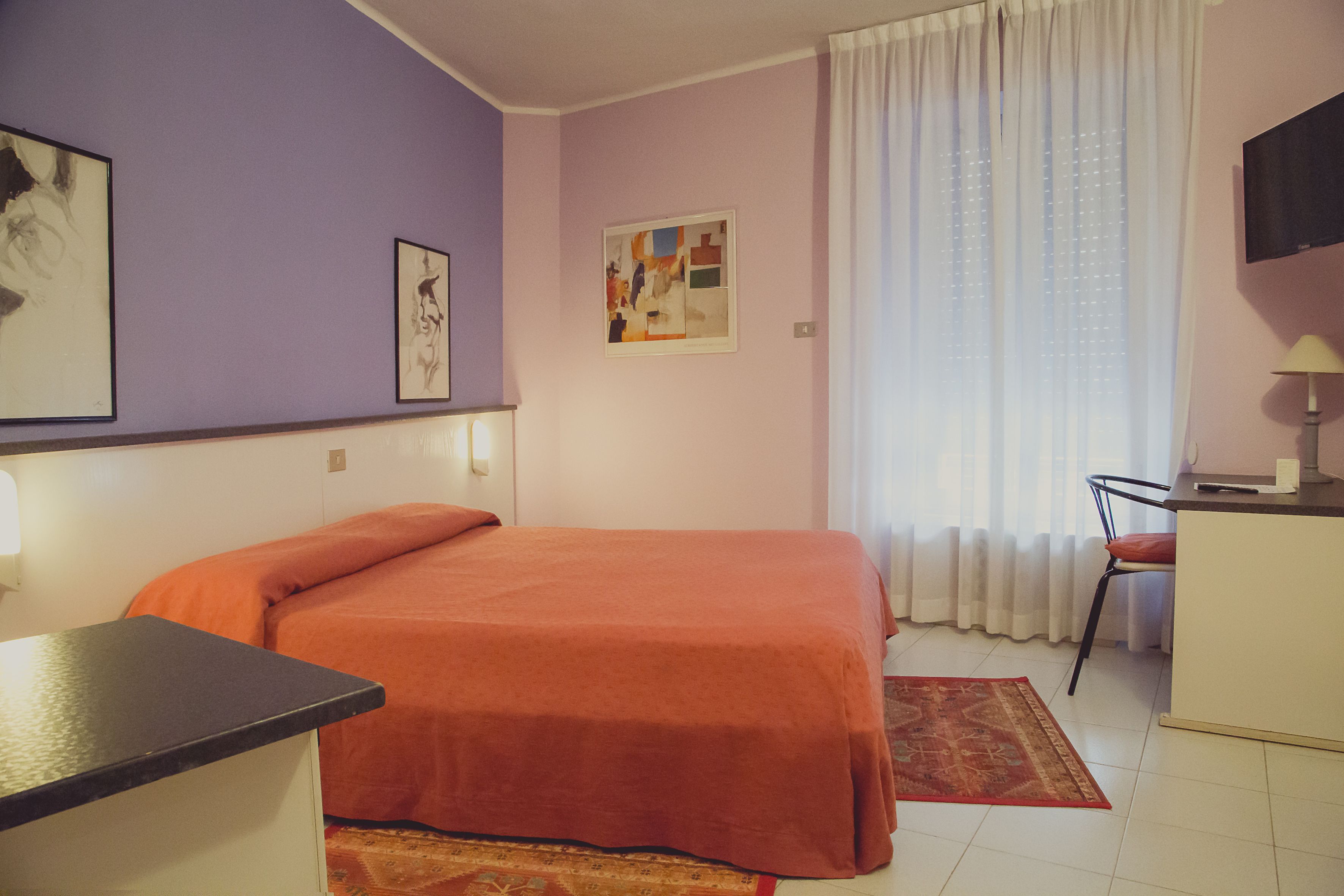 A room with a bed, a desk, a chair, and a TV.