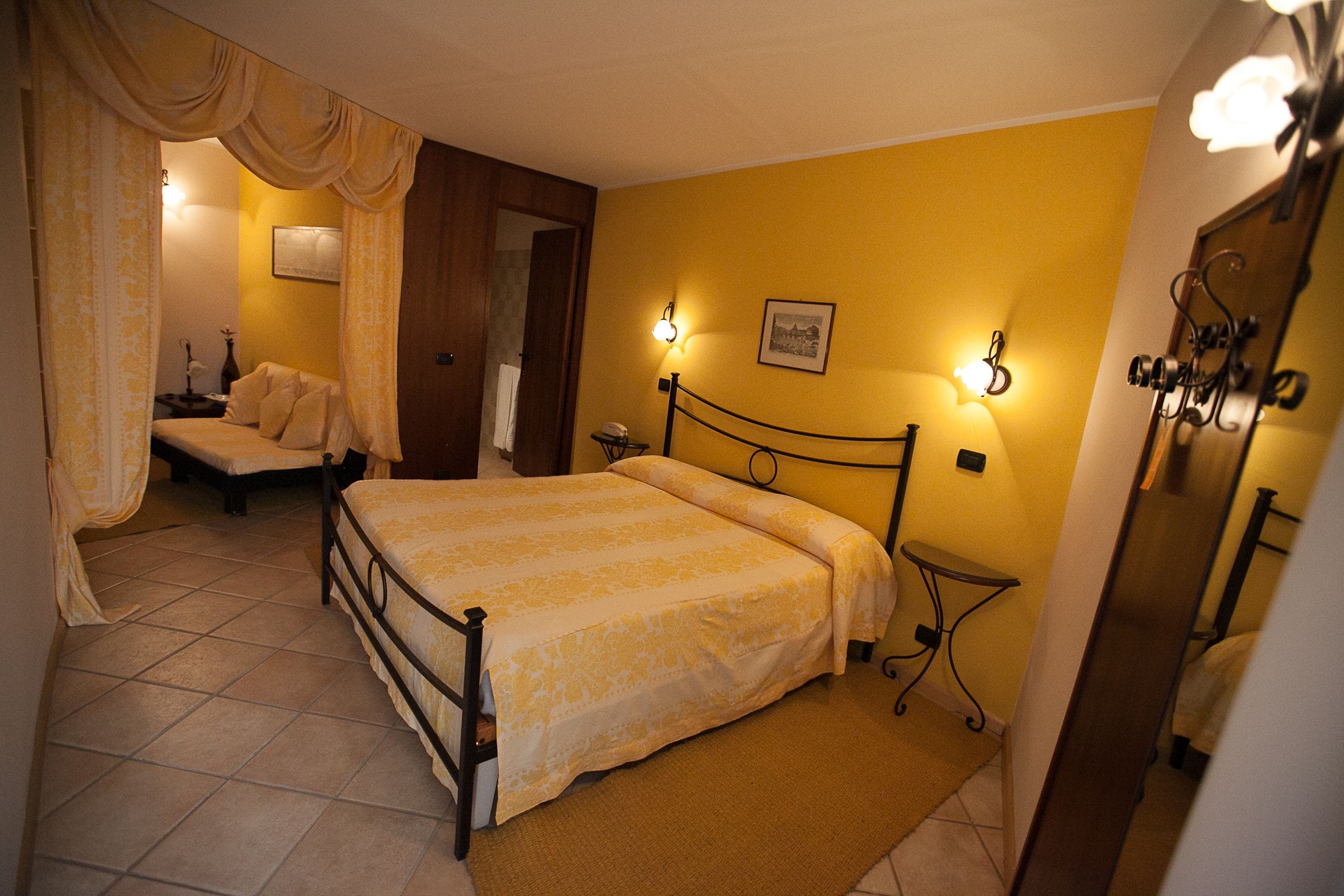 A bedroom with a bed, bedside tables, a nightstand, and a mirror.