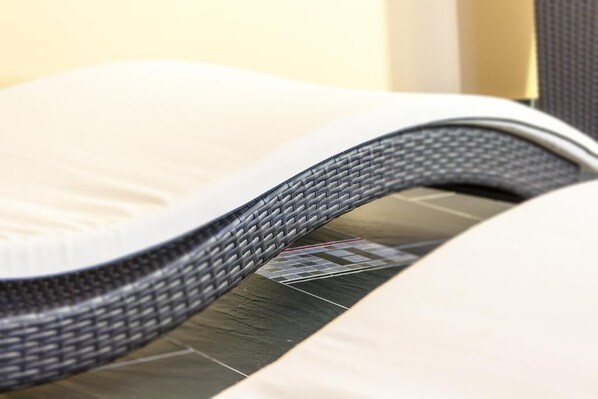A wicker chair with a cushion, placed on a tiled floor. - Landhotel Alt-Jocketa (Poehl)