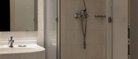 Une salle de bain moderne avec une douche à parois de verre, un lavabo blanc et un miroir au-dessus du lavabo.