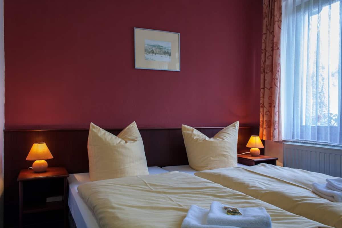 Una habitación de hotel con dos camas, un cuadro en la pared y una ventana con cortinas.