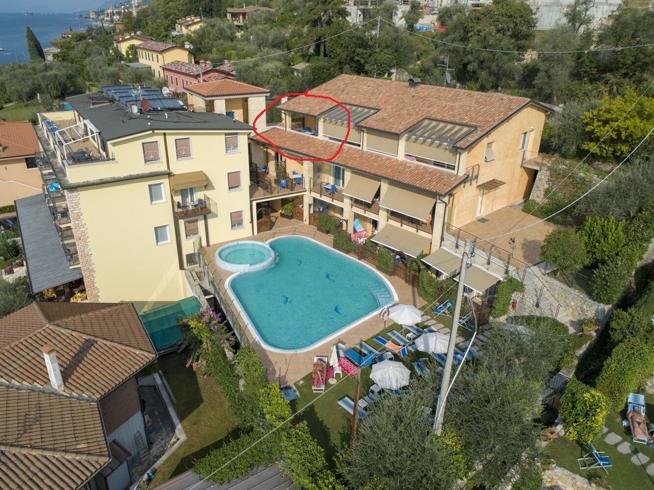 A residential building with a swimming pool, multiple balconies, and a view of the sea.