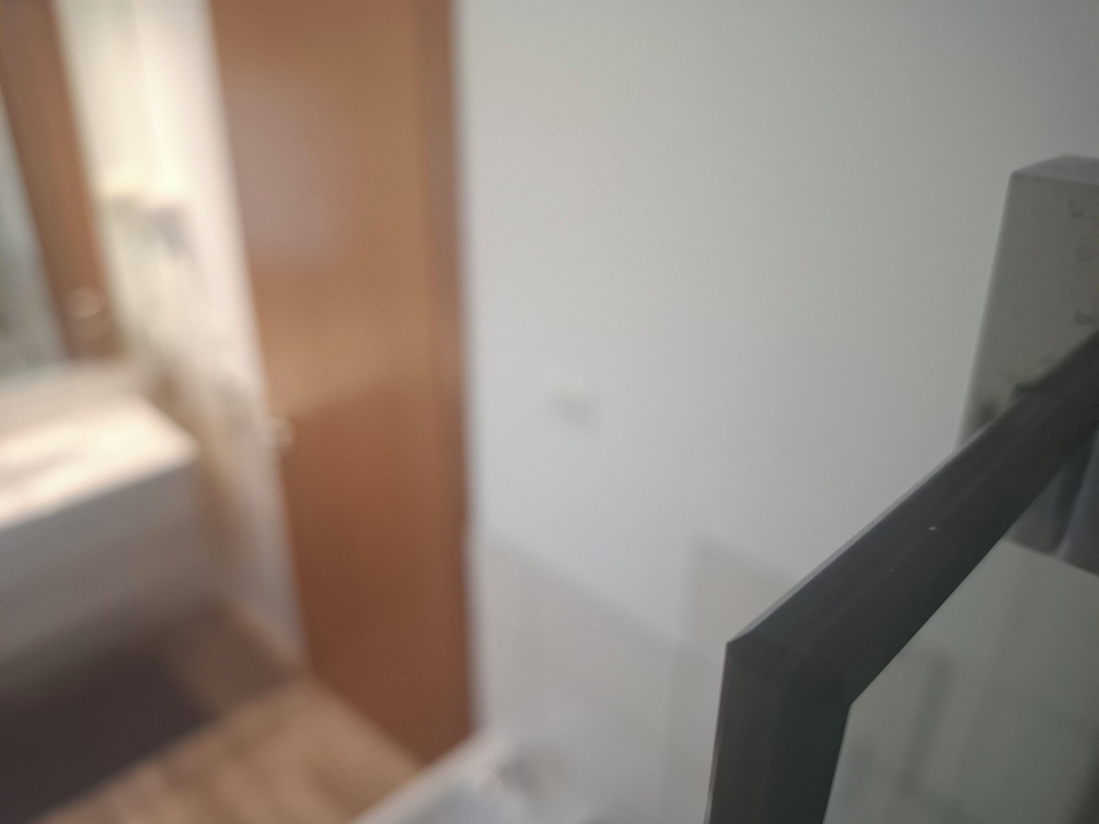 Un gros plan d’une porte en bois donnant sur une pièce dont le mur est blanc et qui est agrémentée d’une rambarde en métal noir.