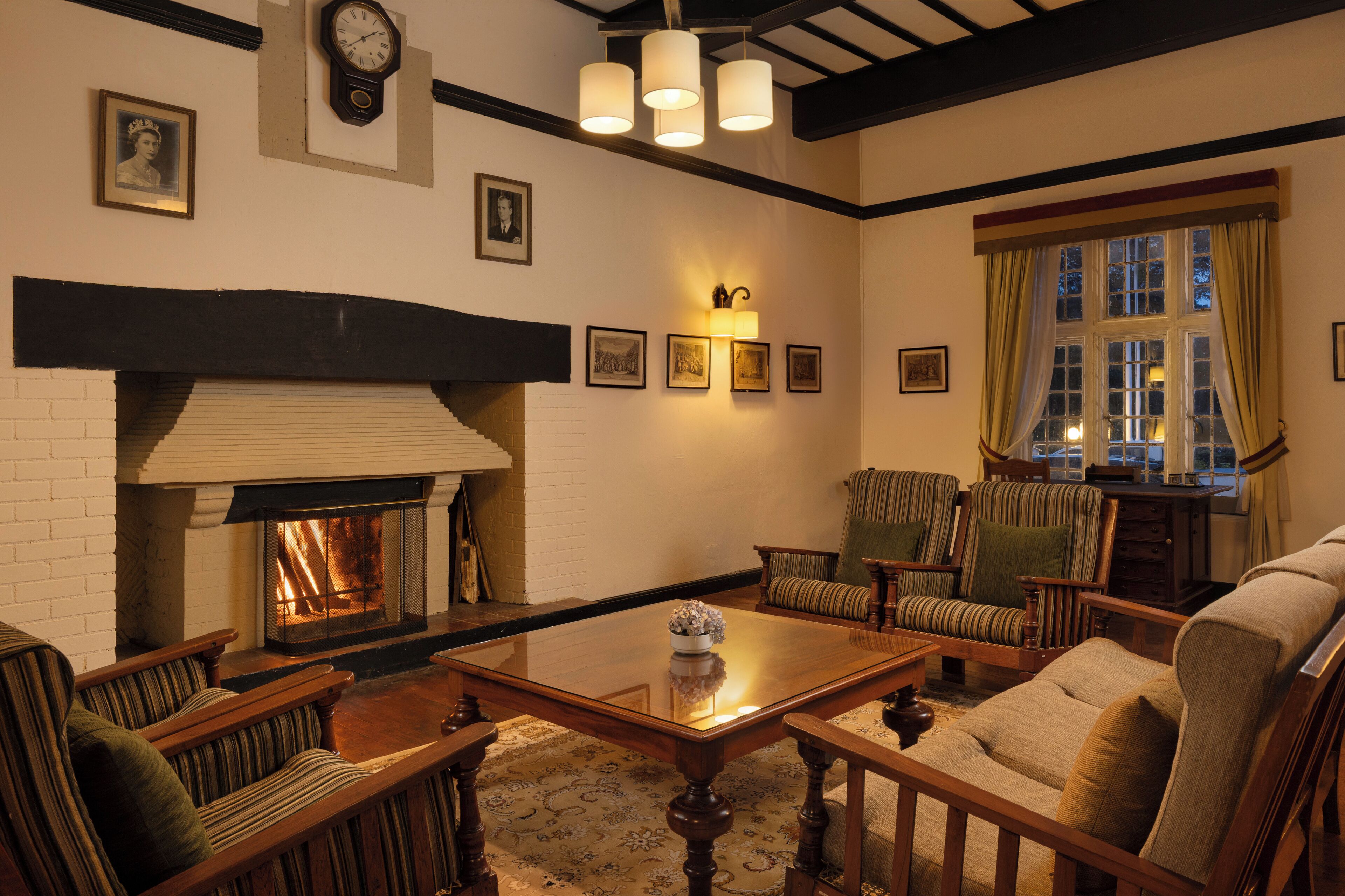 A cozy living room with a fireplace, wooden furniture, and framed pictures on the wall.