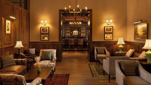 Een klassieke hotelentree met houten lambrisering, een bar en zitgedeeltes.