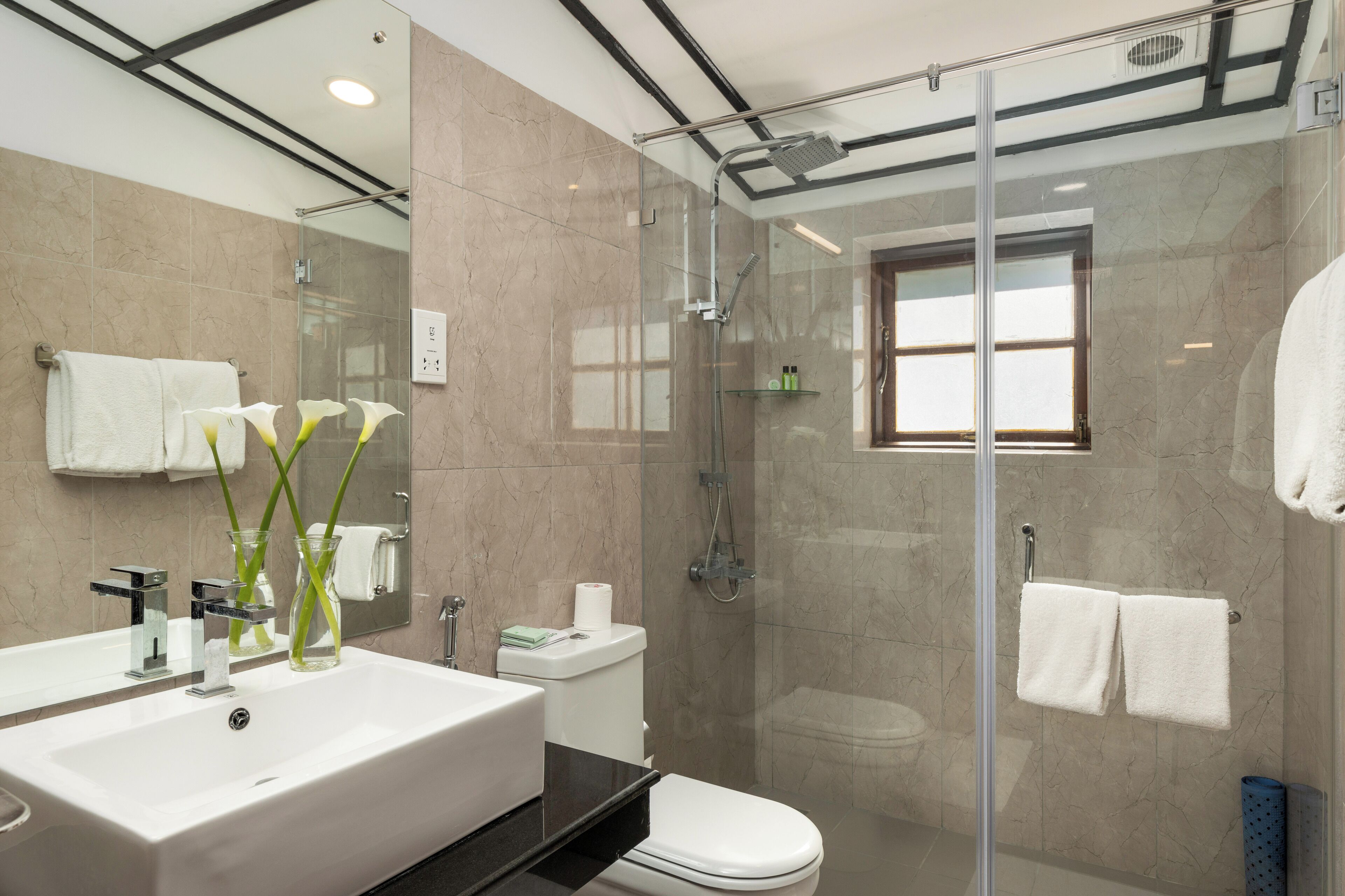 Un baño moderno con cabina de ducha de vidrio, un lavabo amplio y un inodoro.