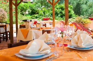 An outdoor dining area with tables set for two, featuring neatly folded napkins, wine glasses, and a bottle of champagne. - Hotel Maladroxia (Sant'Antioco)