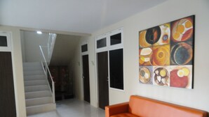 A hallway with a staircase, a large orange sofa, and a colorful abstract painting on the wall.
