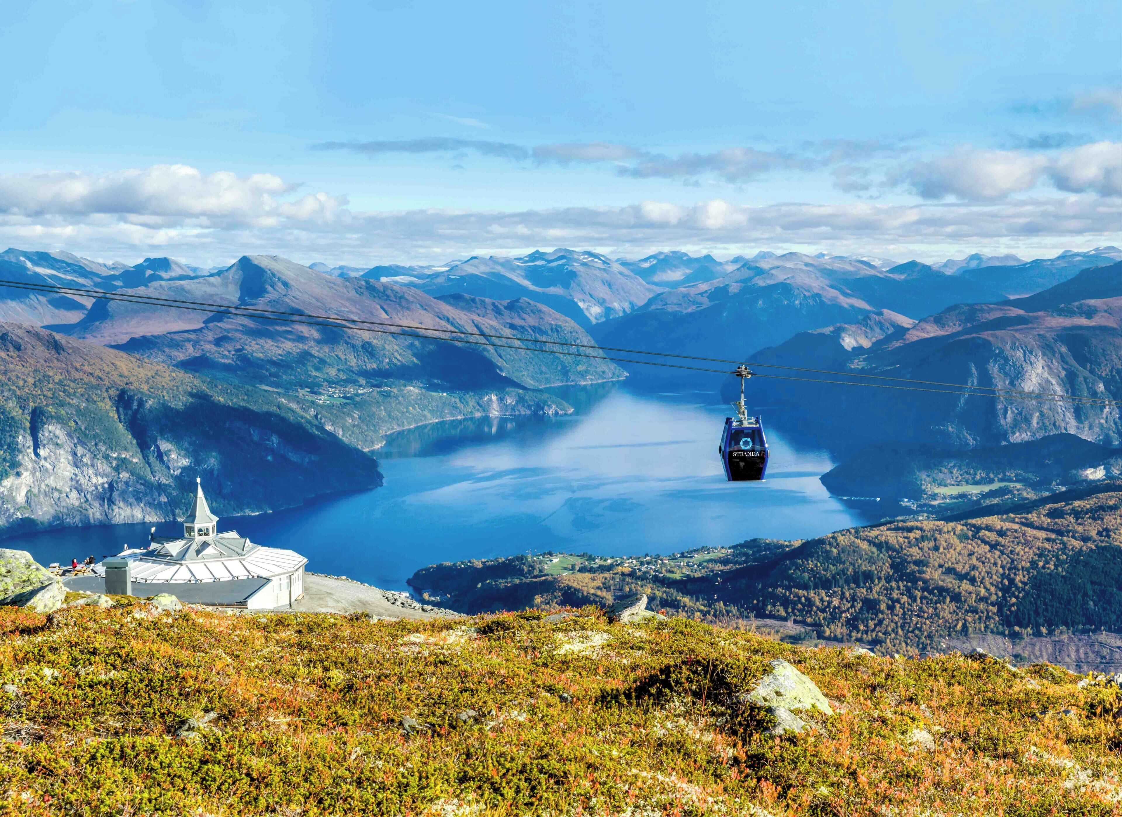 A cable car system with a mountainous landscape and a body of water in the background.