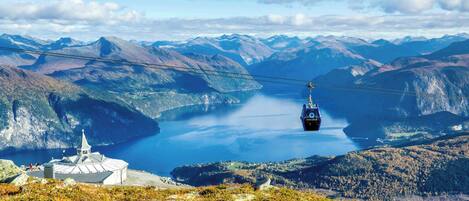 A cable car system with a mountainous landscape and a body of water in the background.