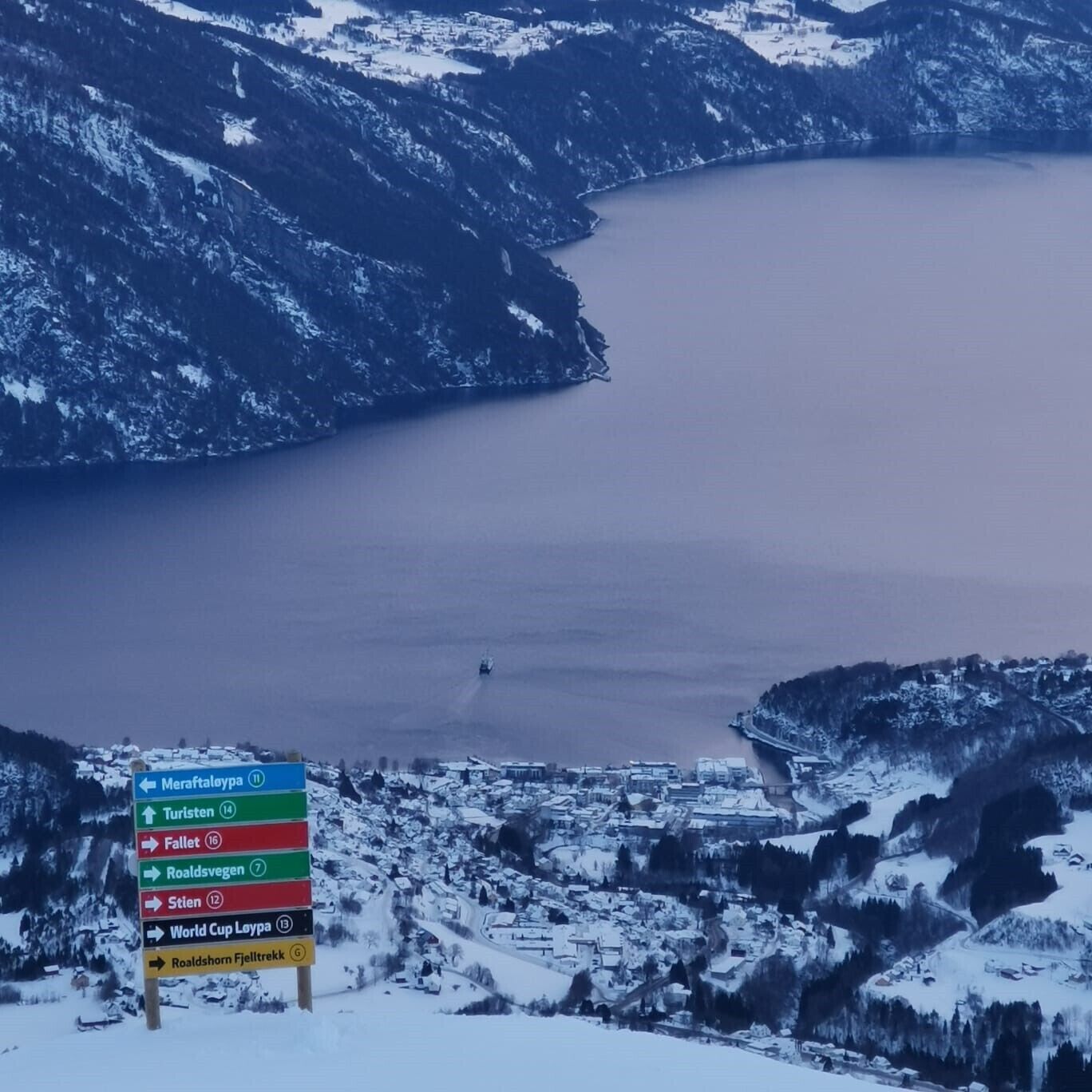 A signpost with directions to various destinations including Meraftaloya, Turisten, Fallet, Roaldsvagen, Stien, World Cup Loypa, and Roaldshorn Fjelltrekk.