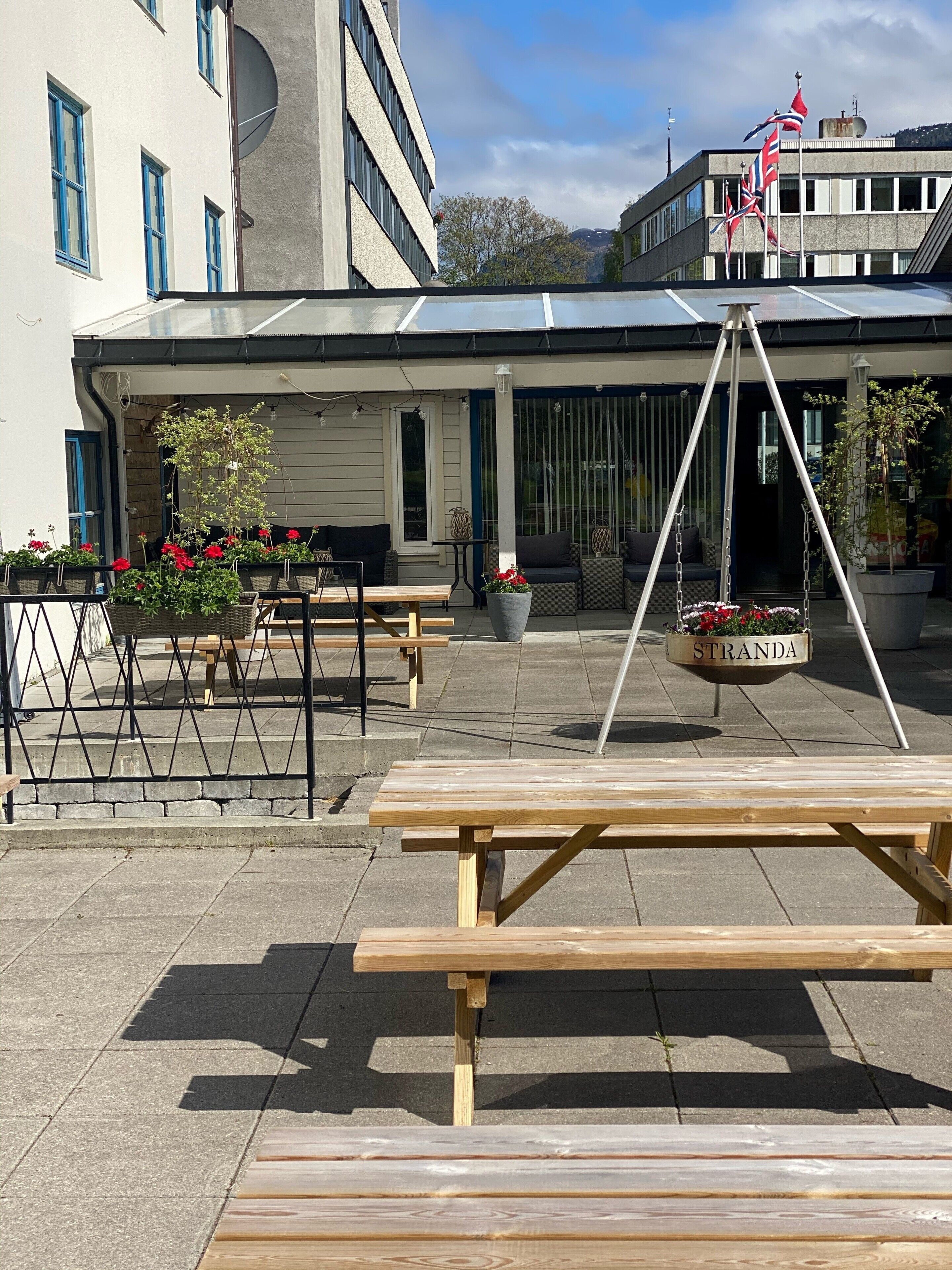 Un espace extérieur aménagé en terrasse, avec des tables de pique-nique en bois et des plantes en pot.
