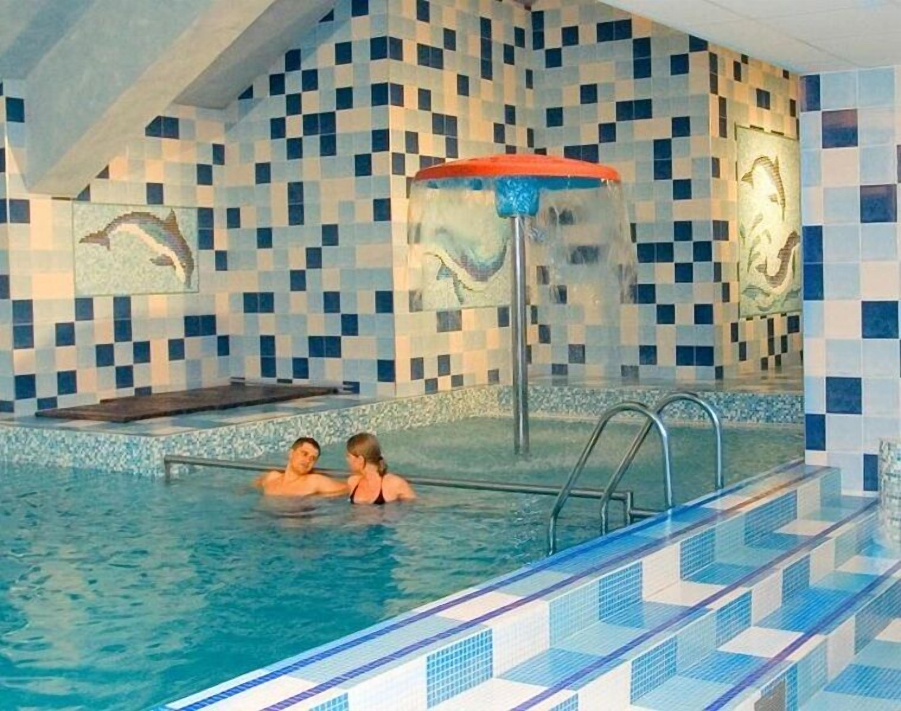 An indoor swimming pool with tiled walls and a clear blue pool.
