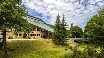 A building with a green roof, surrounded by trees and a grassy area.
