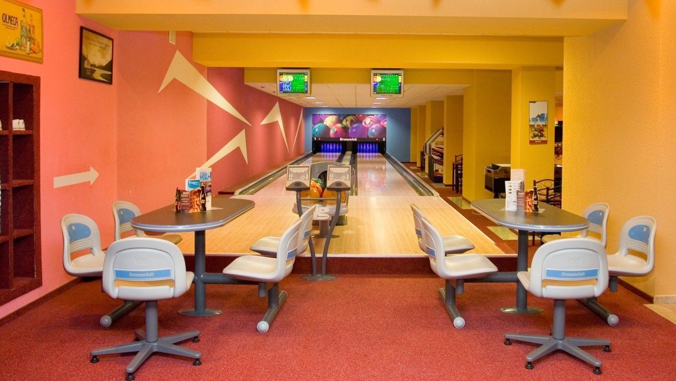 A bowling alley with multiple lanes, seating areas, and a visible scoreboard.