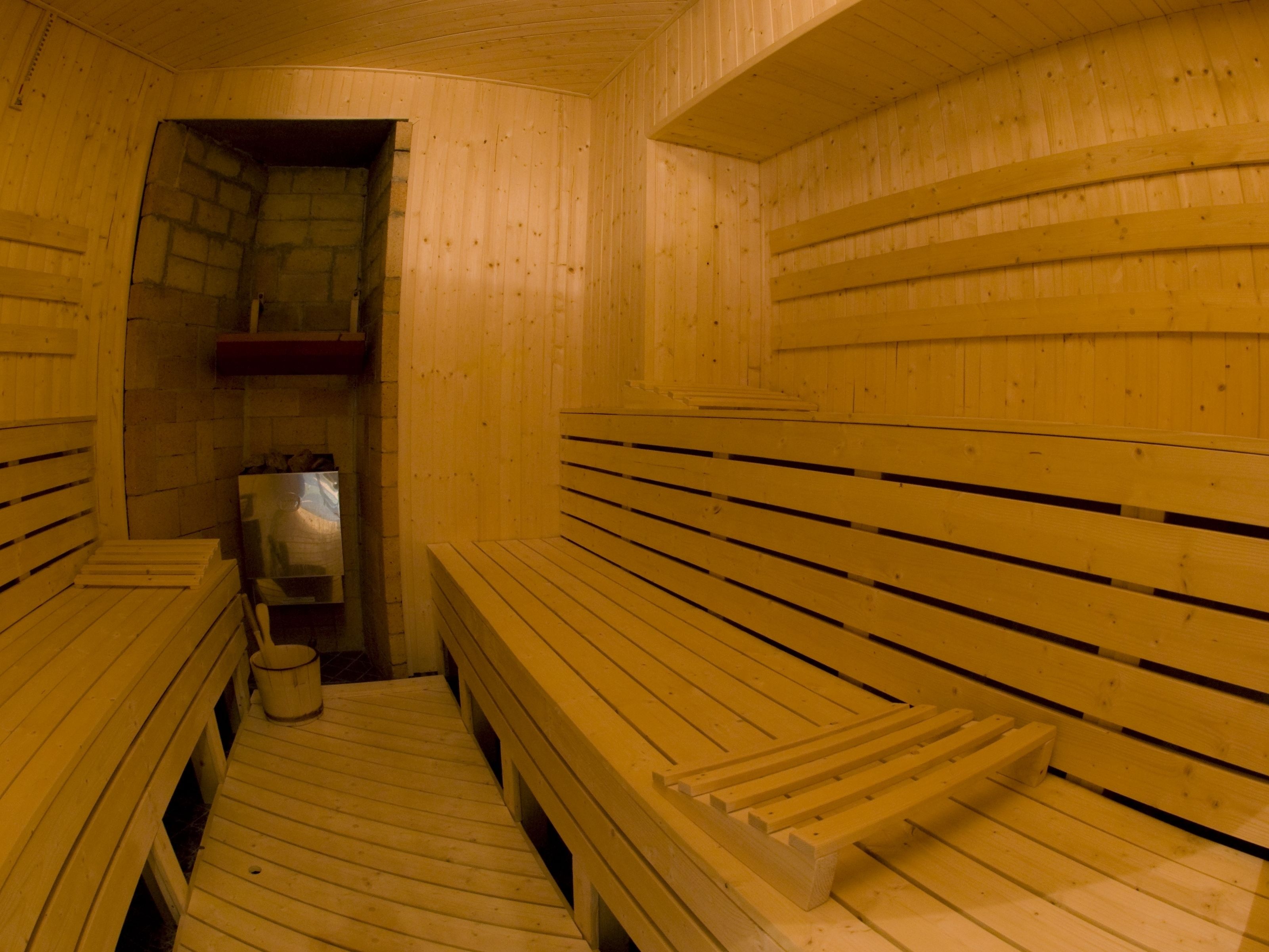 Eine Sauna mit Holzbänken und einer Steinwand.