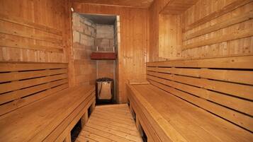 Una sauna de madera con bancos a ambos lados y una pared de piedra en el centro.