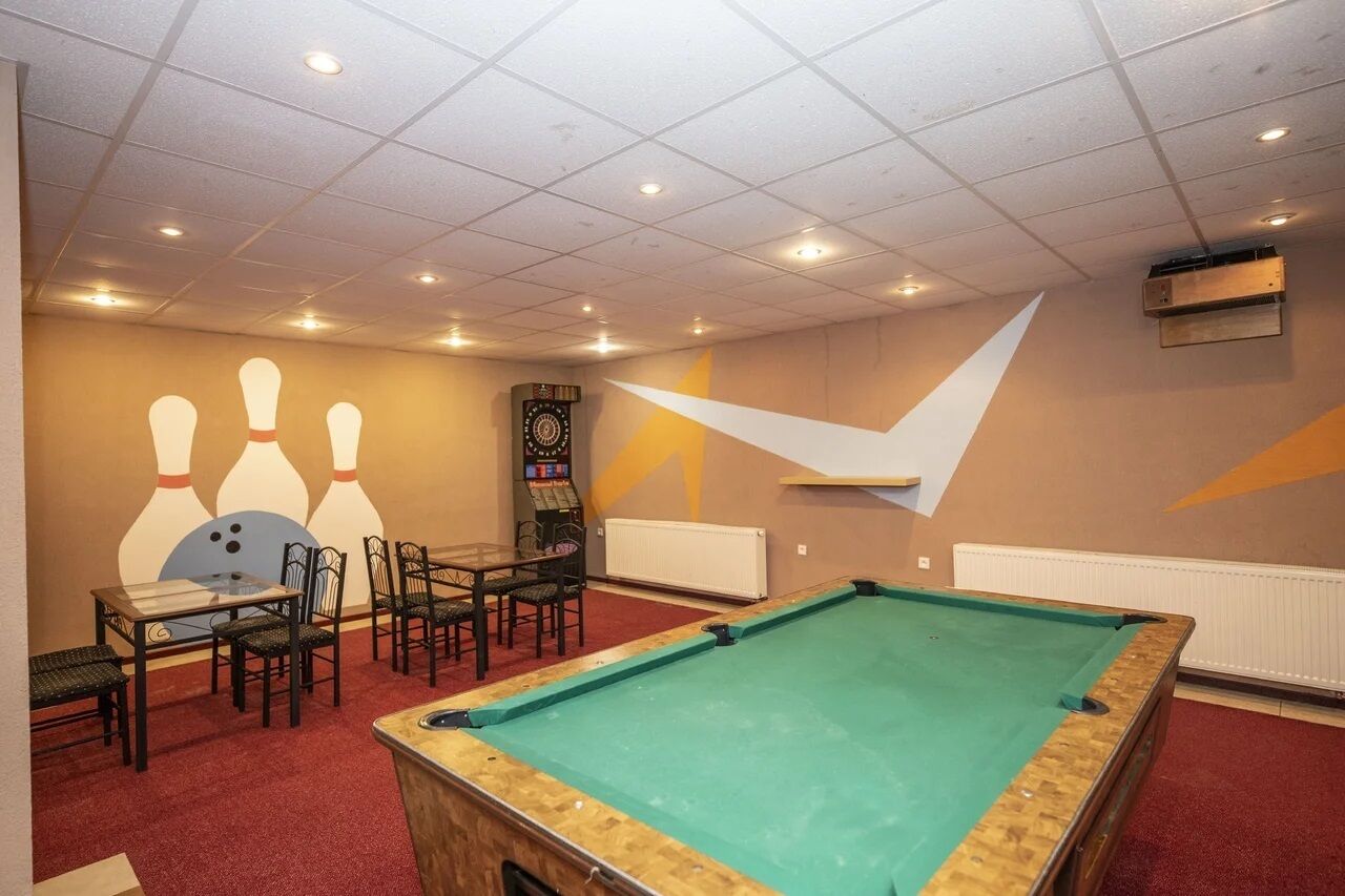 Una sala de billar con mesa de billar, sillas y un mural con temática de bolos.