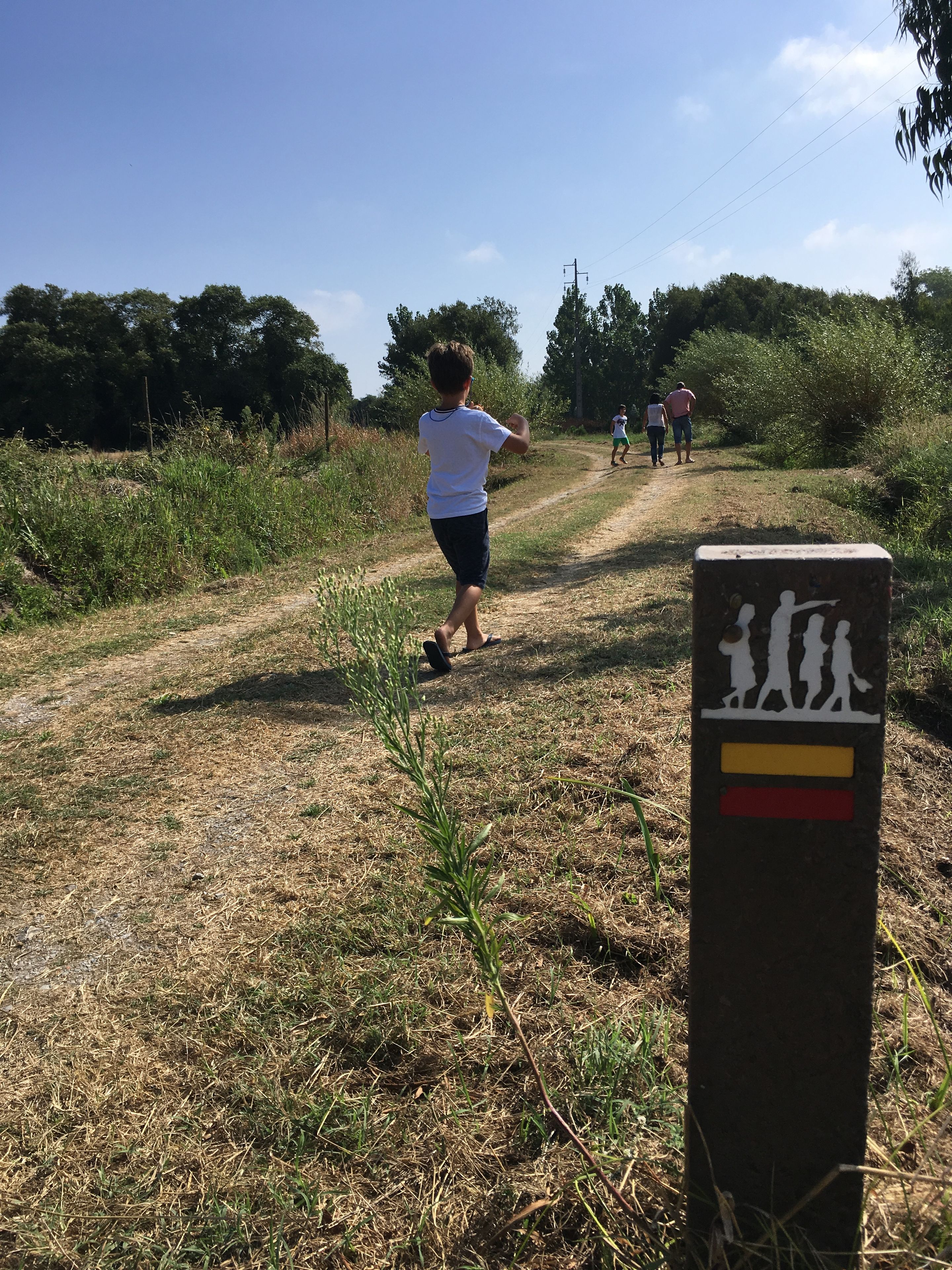 Een onverhard pad met een bord waarop silhouetten van mensen te zien zijn.