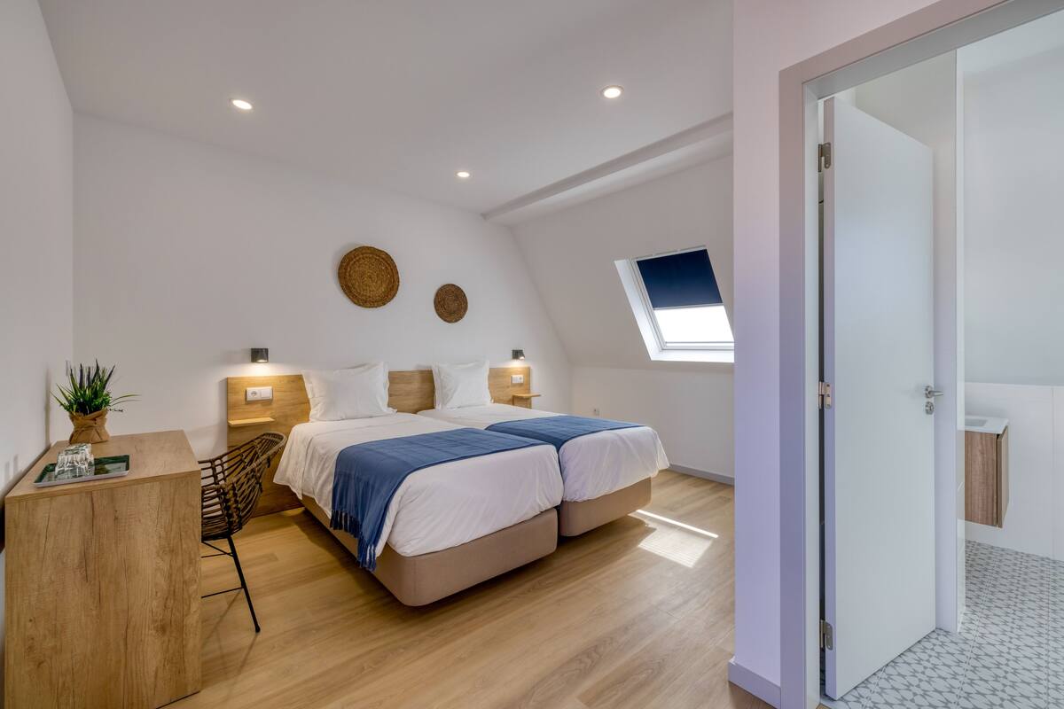 A modern bedroom with a double bed, a desk, and a small window.