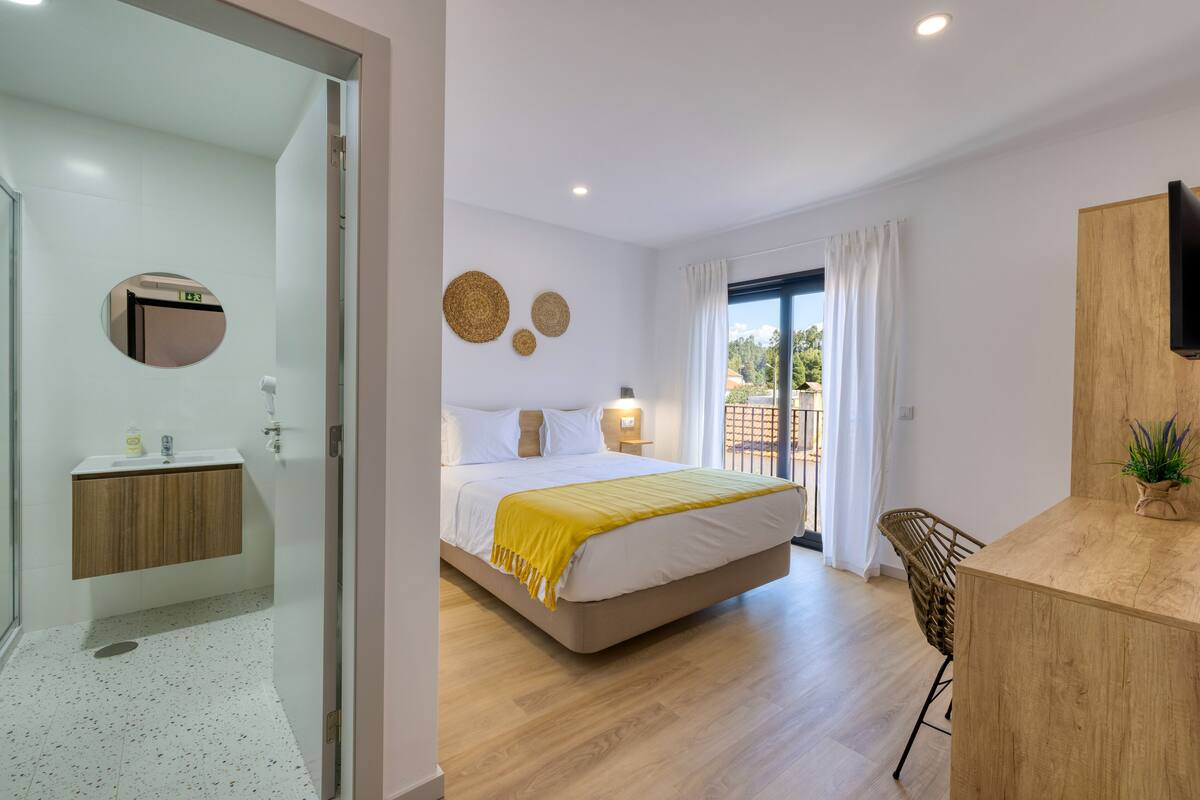 A modern bedroom with a bed, bedside table, and a view of the outdoors.