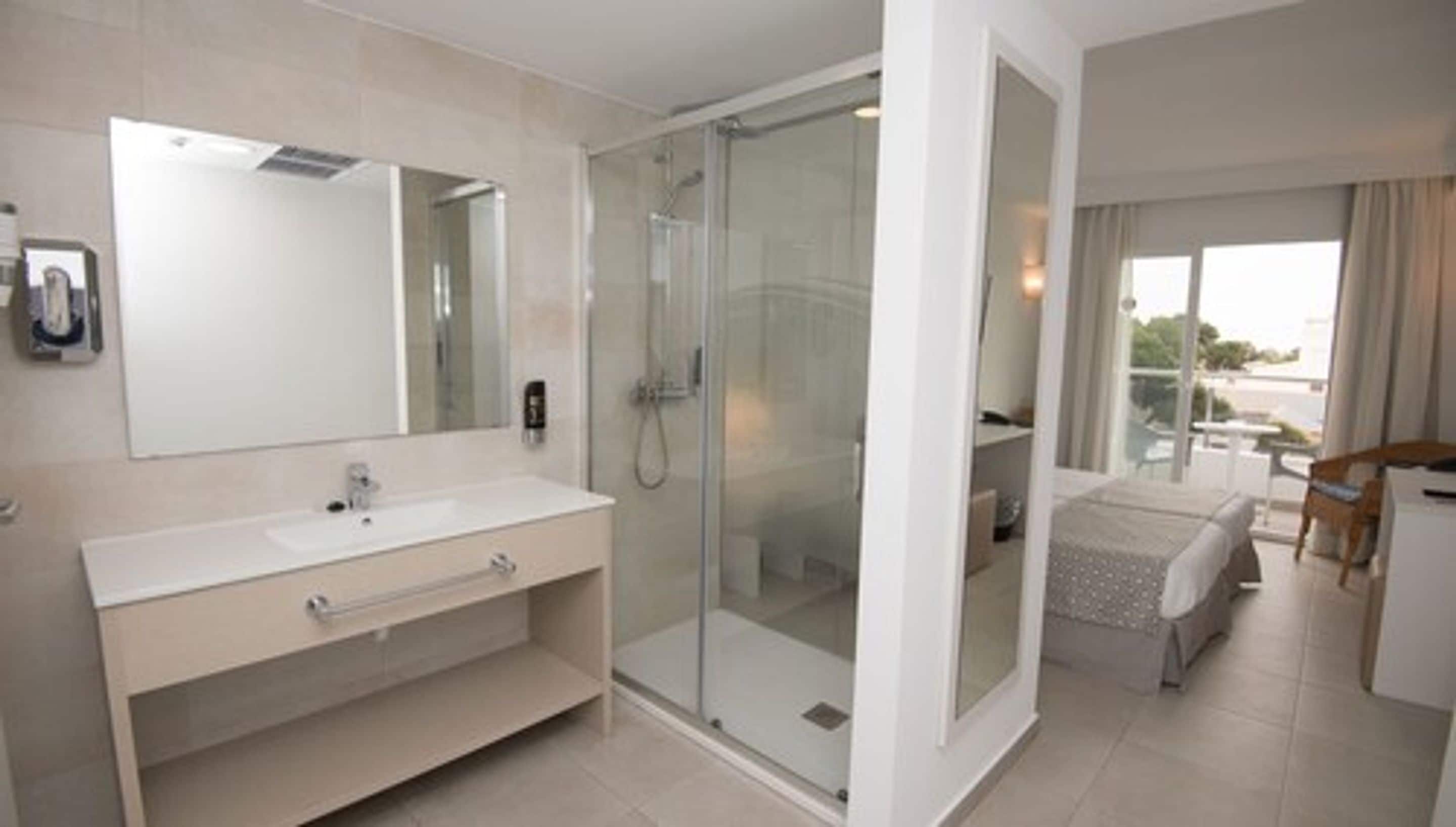 Un bagno moderno con cabina doccia in vetro, uno specchio grande e un mobile lavabo con lavandino e spazio contenitore.
