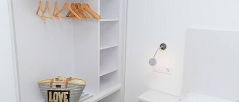 Un placard blanc avec des cintres en bois et un panier portant l’inscription « AMOUR » sur une étagère.