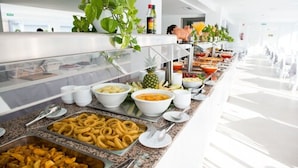 A buffet with various food items including bowls of soup, a pineapple, and trays of onion rings. - Hotel Chevy & Suites (Capdepera)