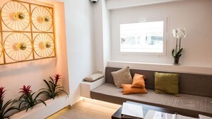 A modern living room with a sofa, cushions, a coffee table, and a wall-mounted decorative piece. - Hotel Chevy & Suites (Capdepera)