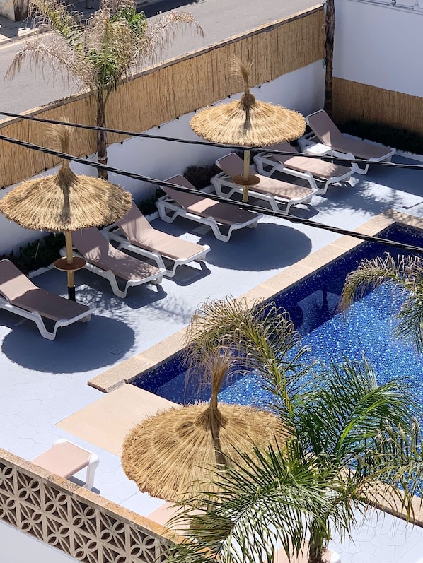 Una piscina al aire libre, sillones reclinables de piscina