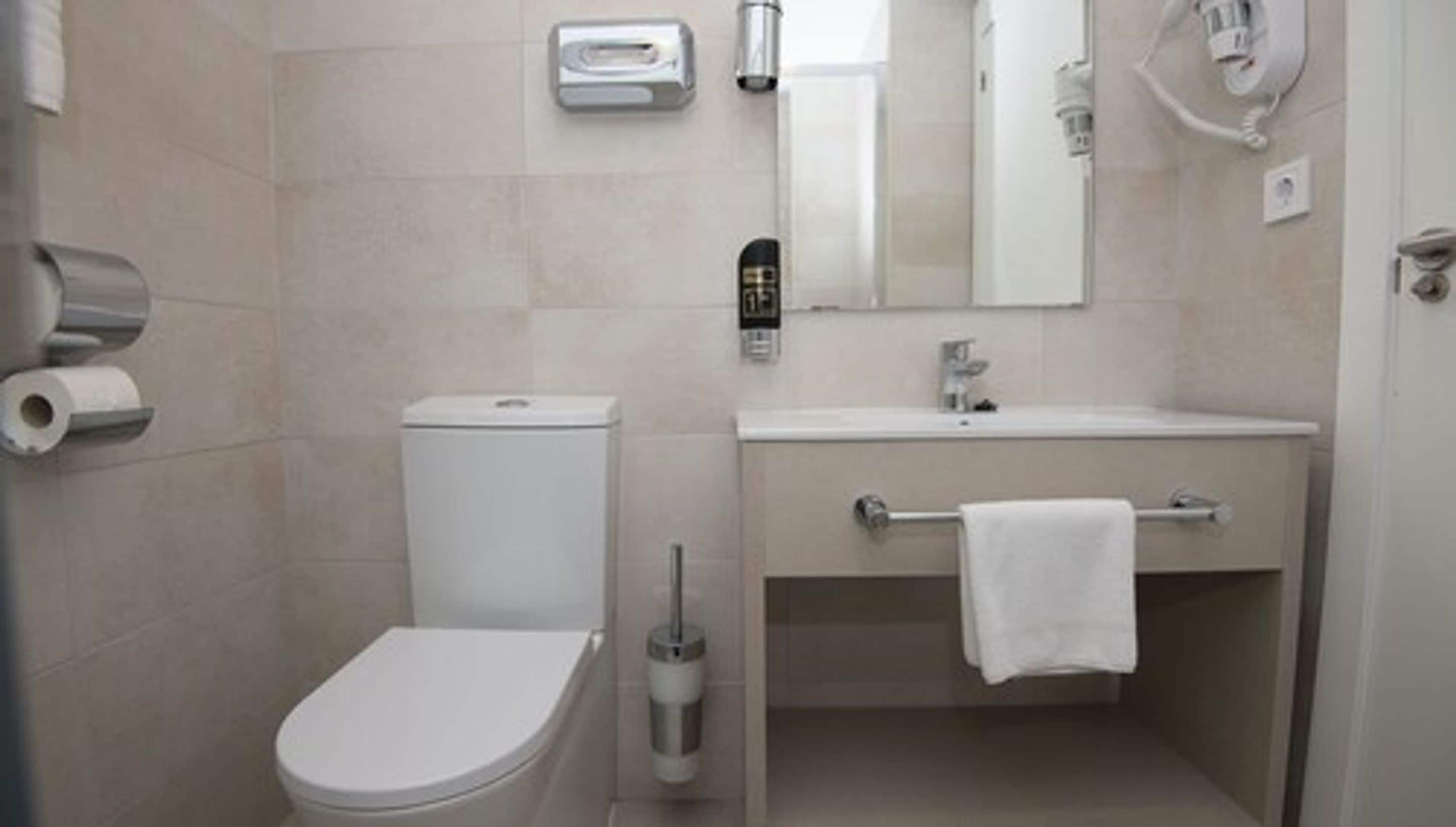A modern bathroom with a toilet, sink, and towel rack.