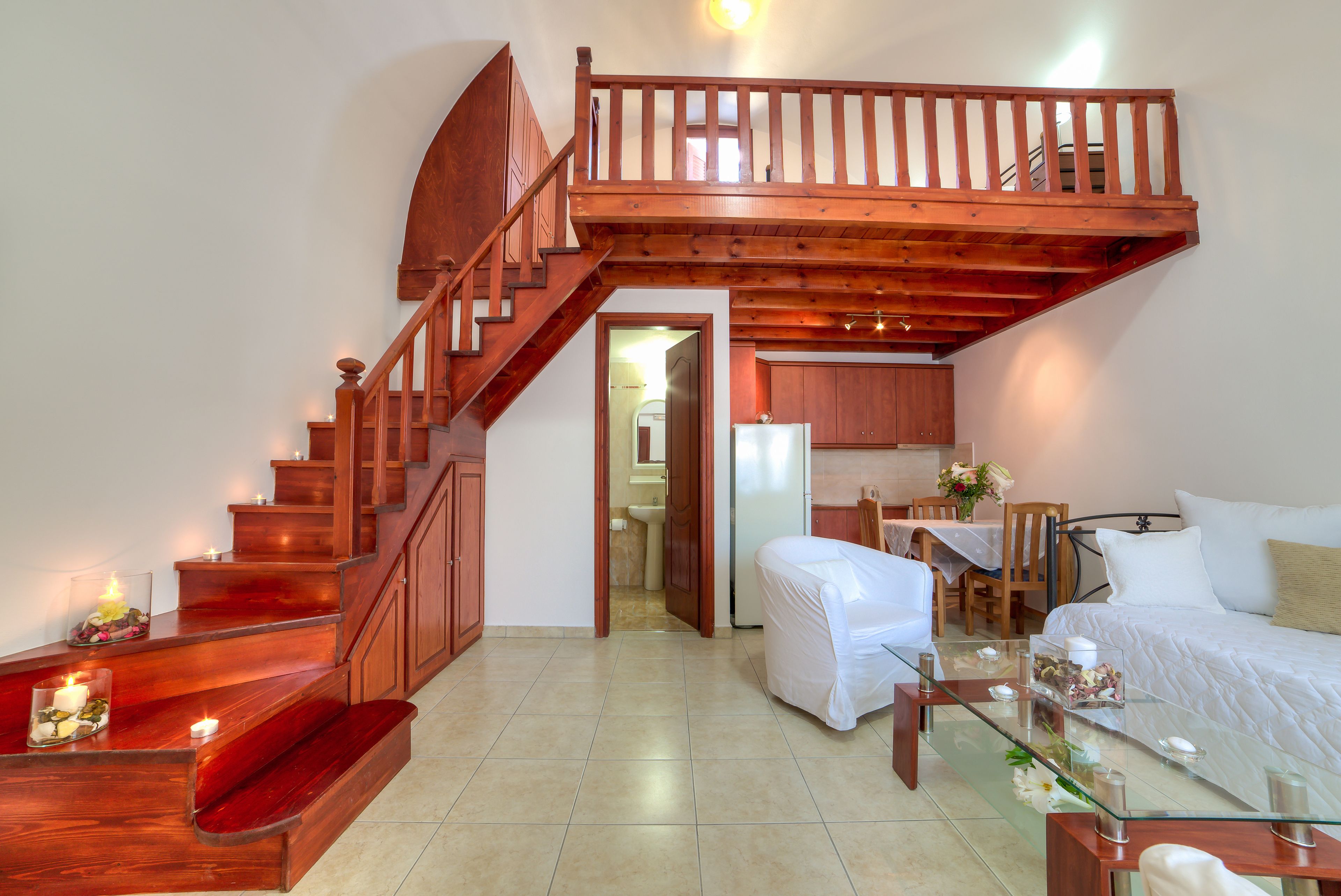 A bedroom with a wooden staircase, a glass table, and a bed.