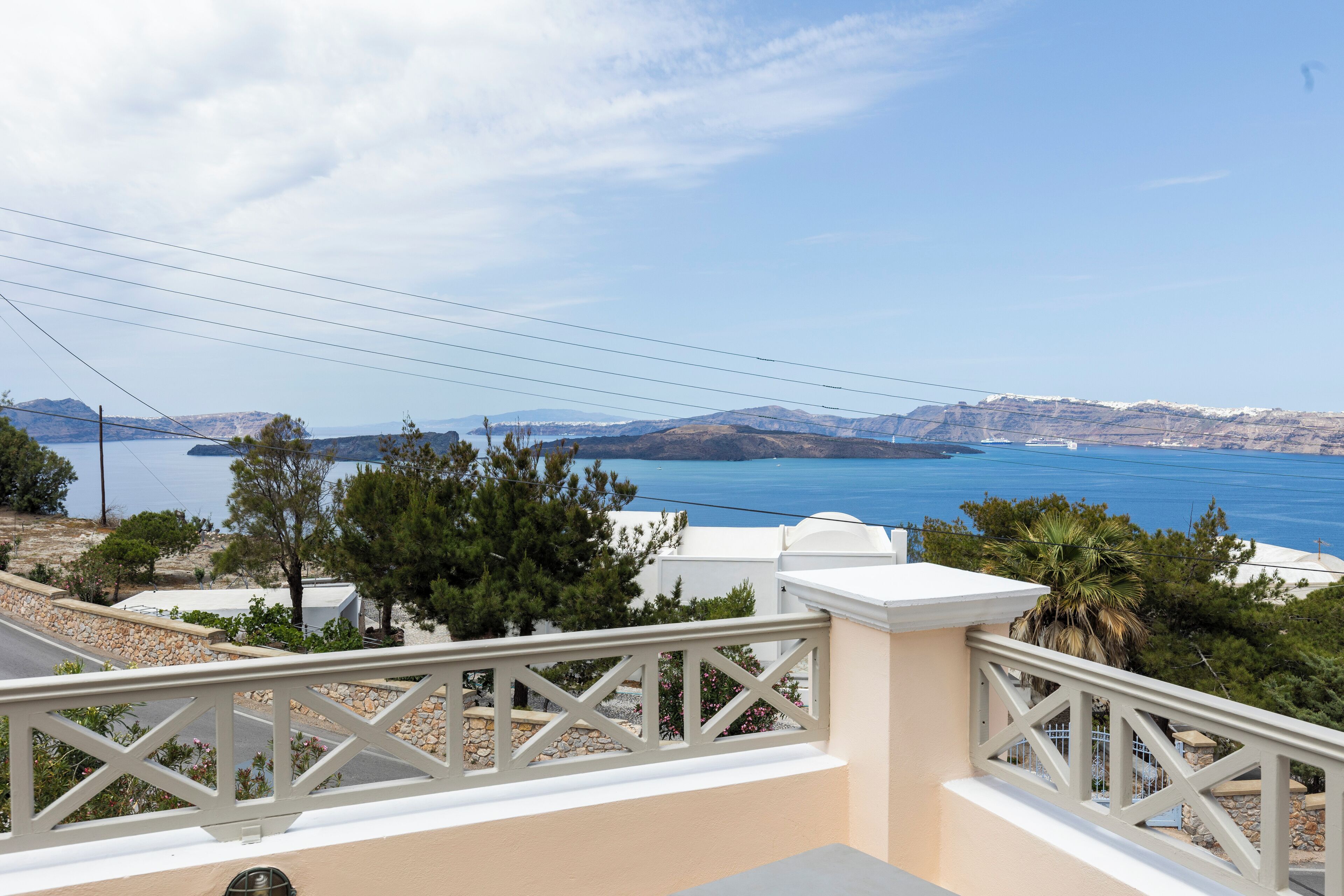 A balcony with a view of a coastal landscape, including a body of water and distant mountains.
