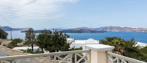A balcony with a view of a coastal landscape, including a body of water and distant mountains.