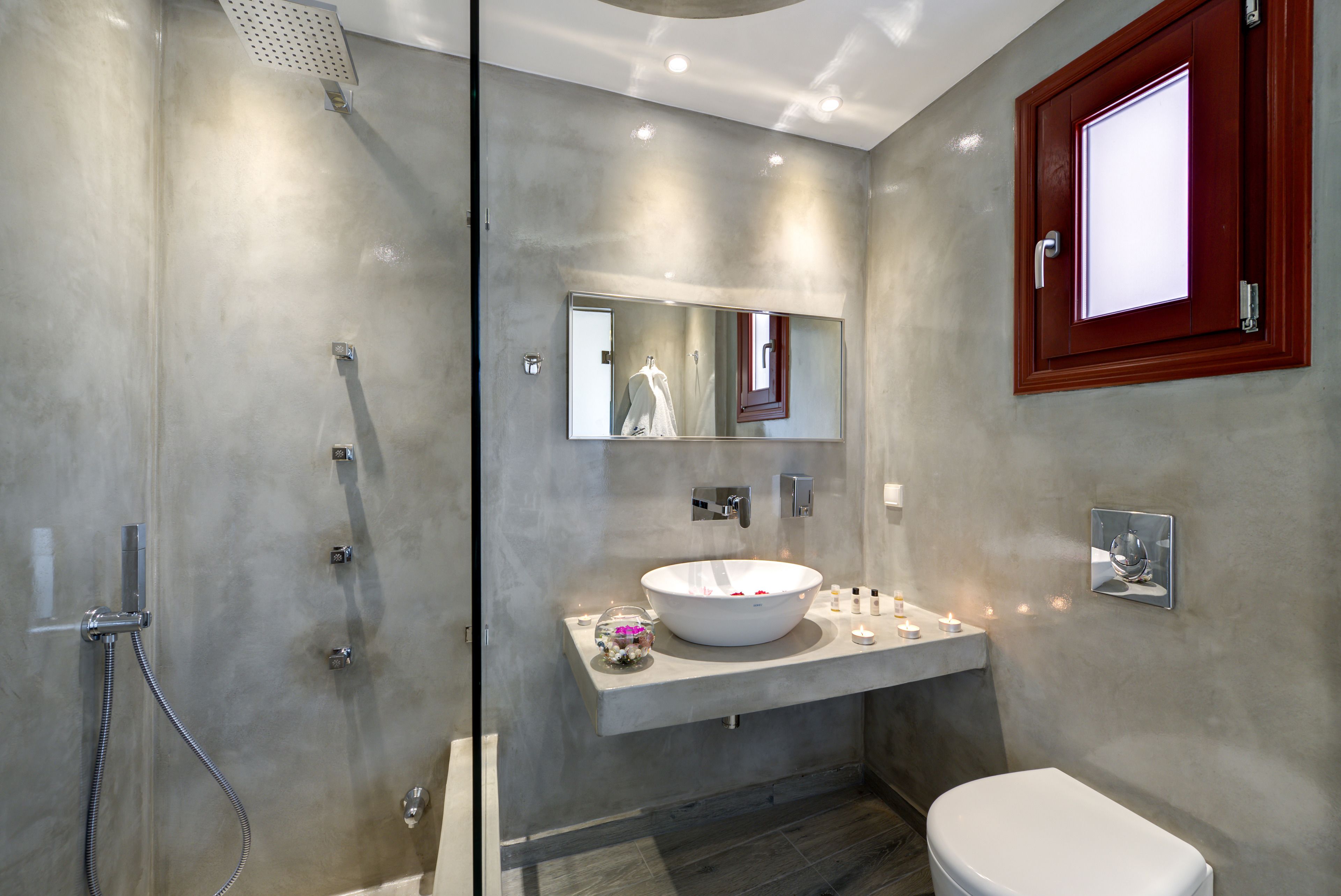 A modern bathroom with a glass-enclosed shower, a large mirror, a white sink, and a toilet.