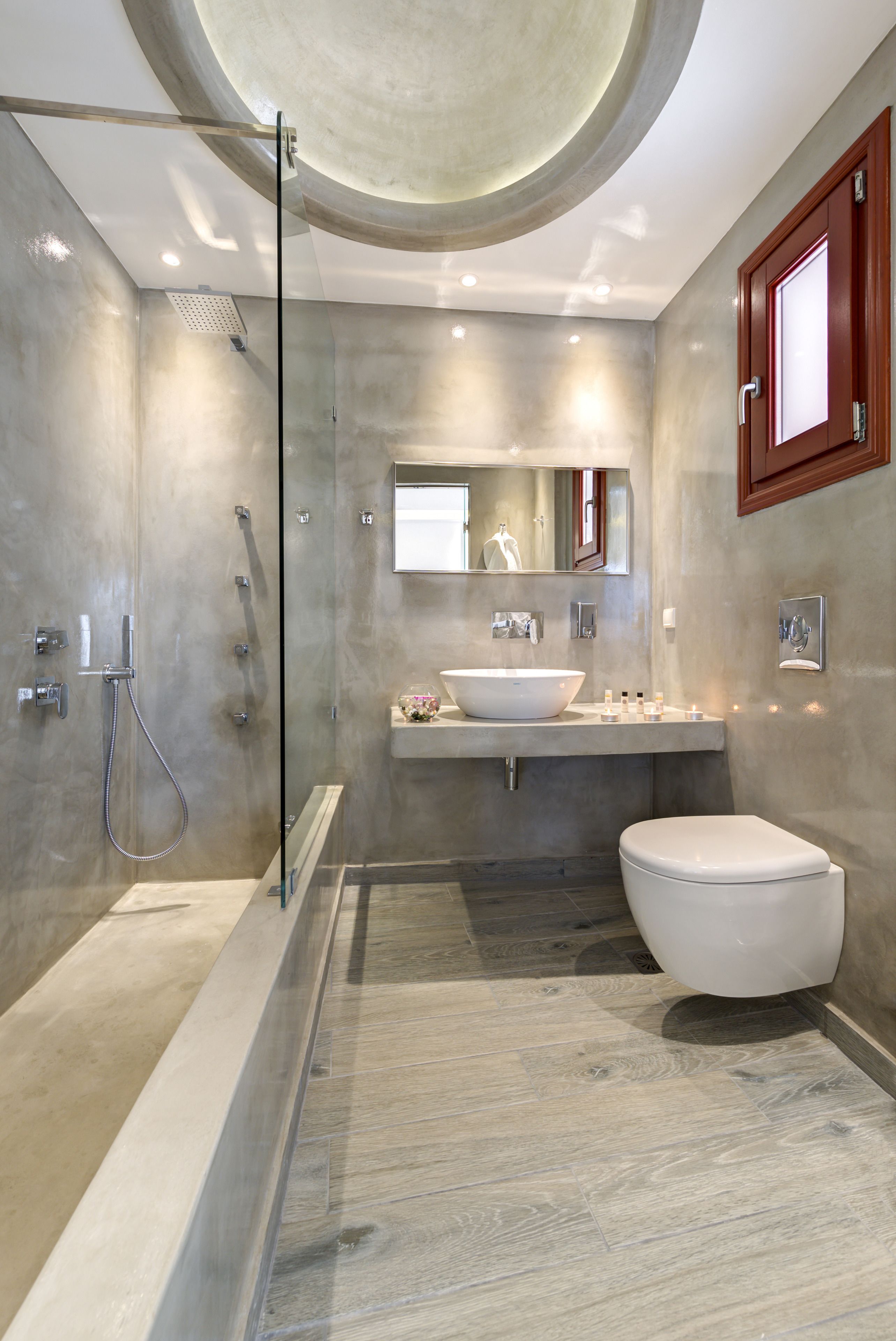 Une salle de bain moderne avec une douche à parois de verre, un grand lavabo sur pied et des toilettes.