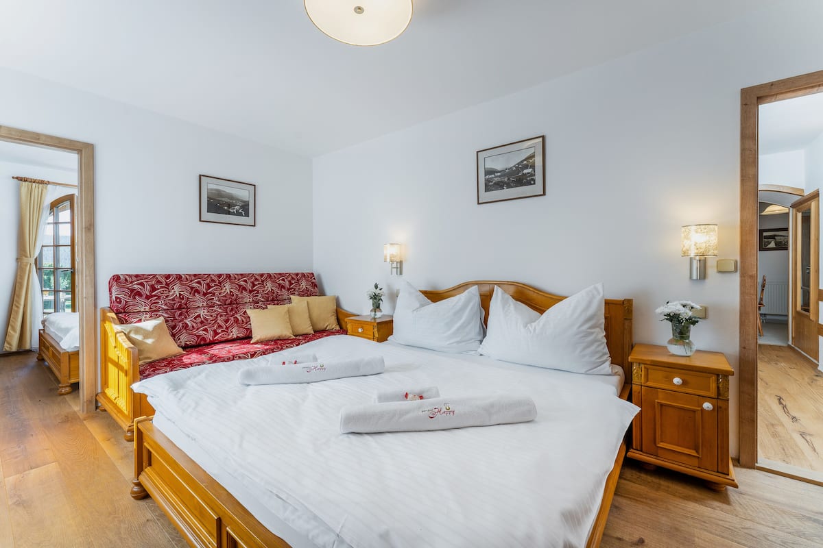 A hotel room with a large bed, two bedside tables, a wooden headboard, and a large mirror.