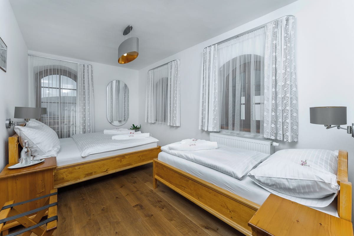 A room with two wooden beds, a wooden desk, a mirror, a lamp, and a radiator.