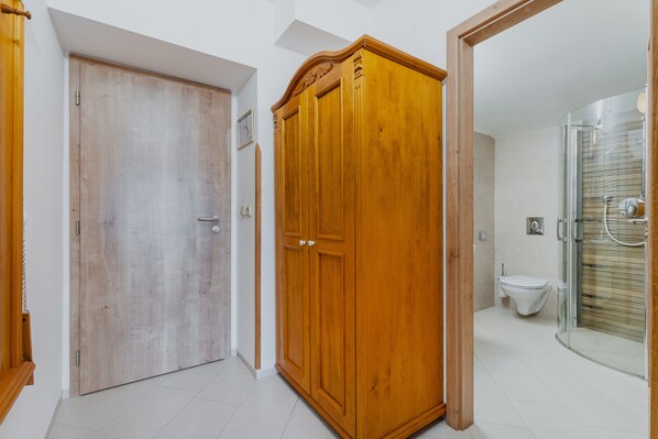 Un pasillo con un armario de madera, una puerta y una cabina de ducha de vidrio.